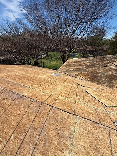 Wide run of new OSB decking installed across a roof plane, bare trees behind in Haslet, TX